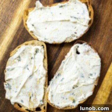 Herb-infused mascarpone generously spread onto a slice of golden toast.