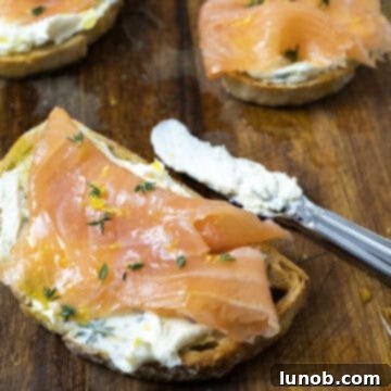 Finished Mascarpone Toast with Lox on a cutting board, garnished with lemon zest and olive oil.