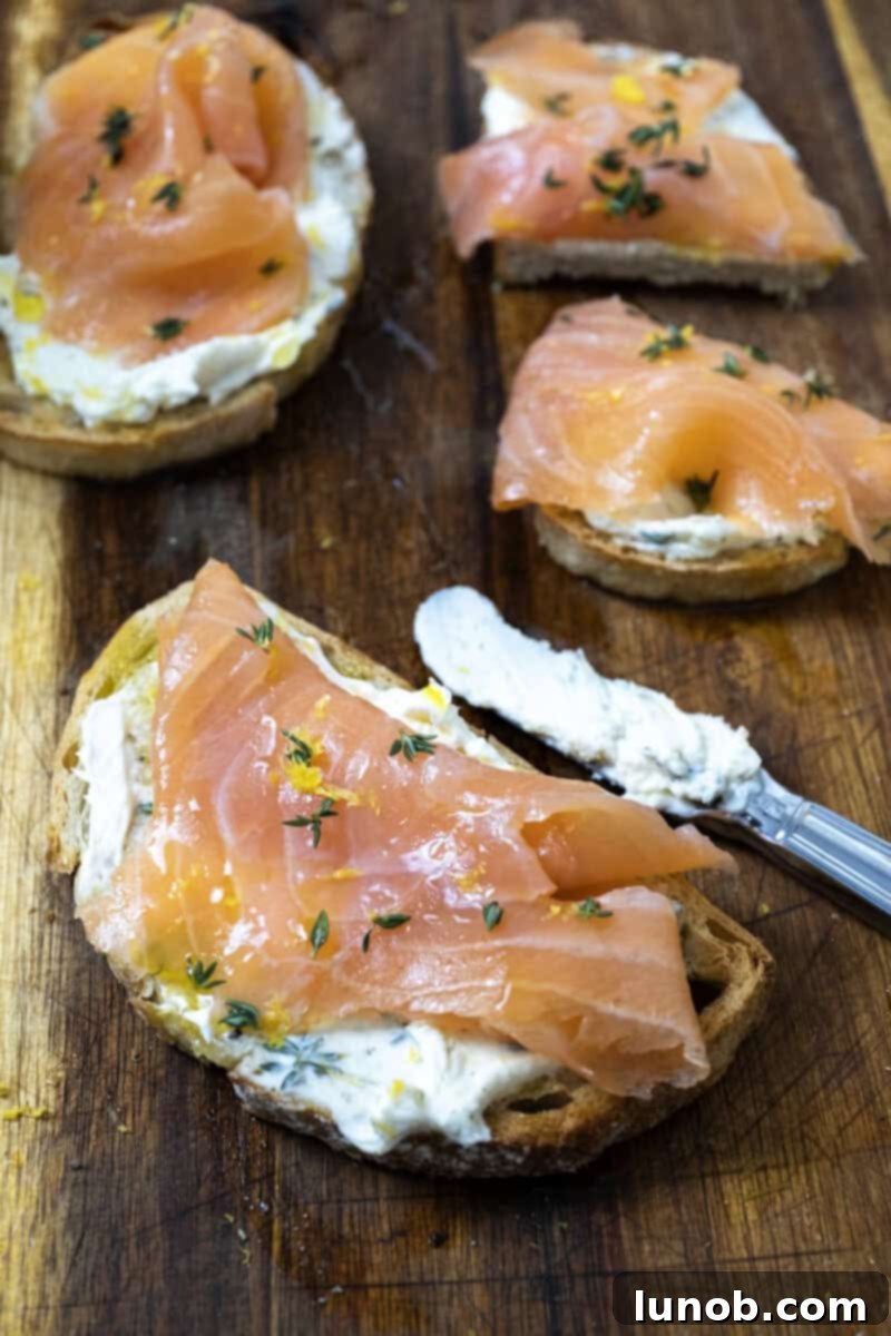Three perfectly prepared Mascarpone Toast with Lox pieces on a wooden cutting board, ready to be served.