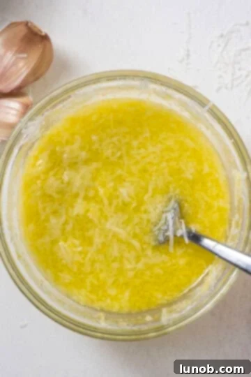 A close-up of a whisk blending Pecorino Romano cheese, lemon zest, and freshly squeezed lemon juice in a small bowl, creating the base for the creamy sauce.