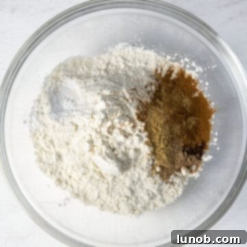 Irresistible Chewy Pumpkin Chocolate Chip Cookies 4 A bowl containing a mixture of dry ingredients: flour, baking soda, baking powder, salt, nutmeg, ginger, cloves, and cinnamon.