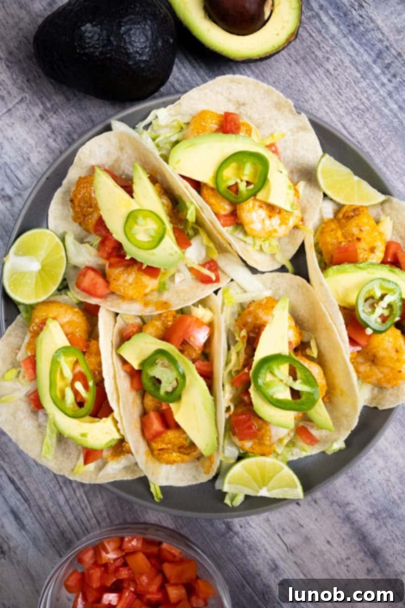 Fiery Volcano Shrimp Tacos 4 Two vibrant Volcano Shrimp Tacos, generously topped with fresh tomatoes, creamy avocado slices, and a hint of green cilantro, with lime wedges on the side, inviting you to take a bite.