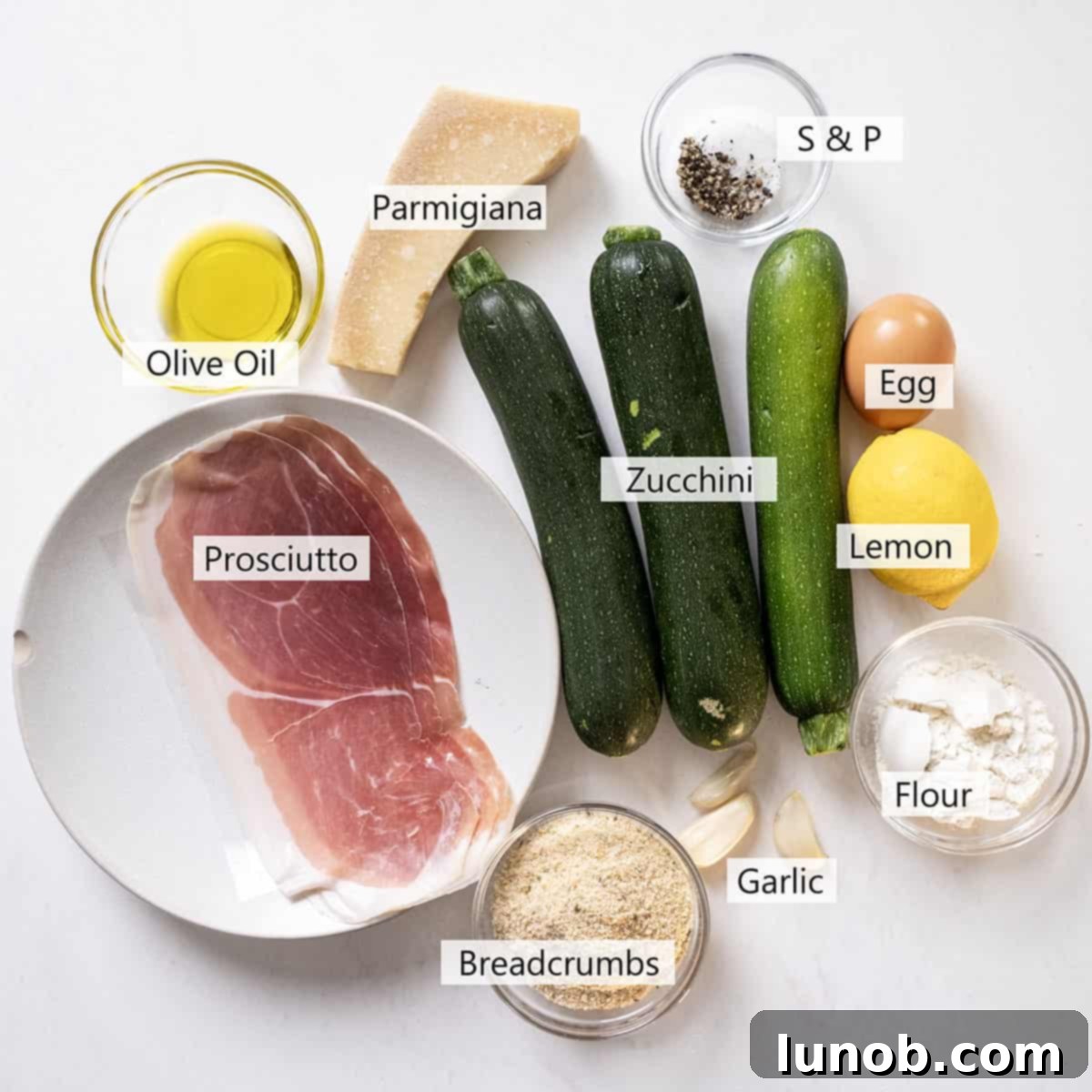 Crispy Air-Fried Zucchini Fritters 4 A spread of fresh ingredients for zucchini fritters, including zucchini, parmesan, prosciutto, and lemon.