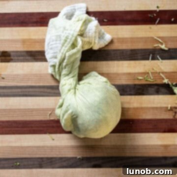 Crispy Air-Fried Zucchini Fritters 6 Grated zucchini being squeezed in a cheesecloth to remove excess liquid.