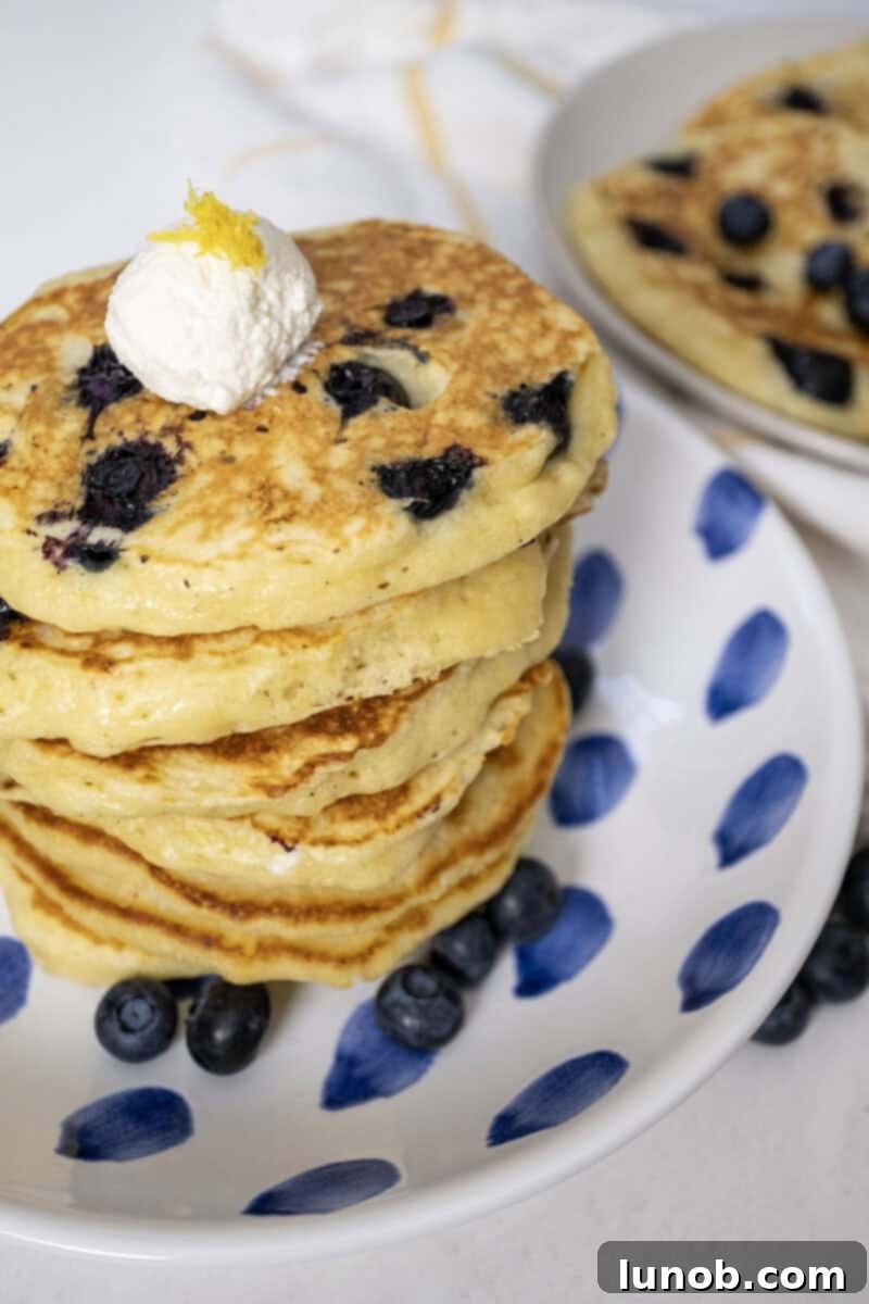 Lemon ricotta blueberry pancakes on a plate with a dollop of ricotta.