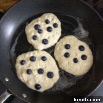 Pancakes with blueberries baking on the frying pan.