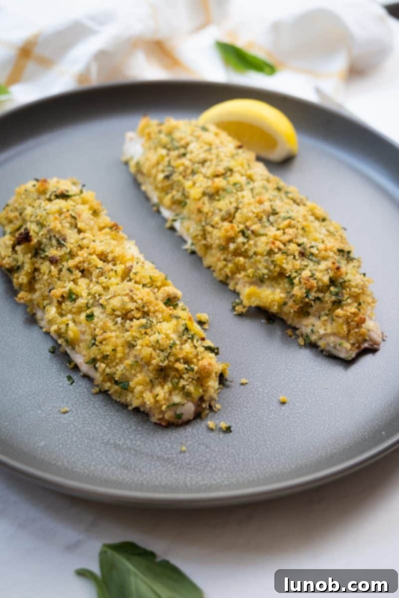 Lemon Pistachio Crusted Snapper on a plate, garnished with lemon
