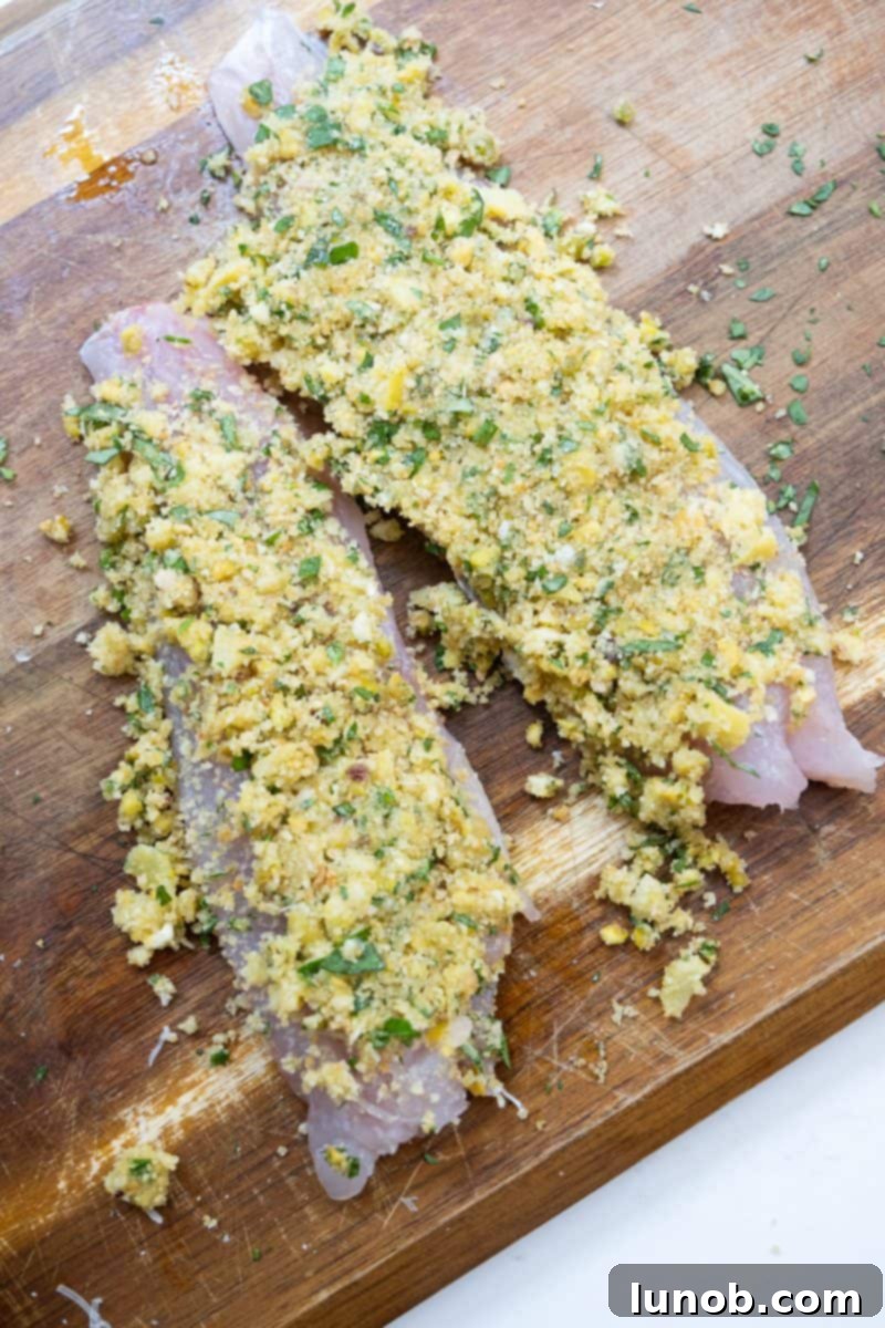 Uncooked lemon pistachio crusted fish fillets on a baking sheet