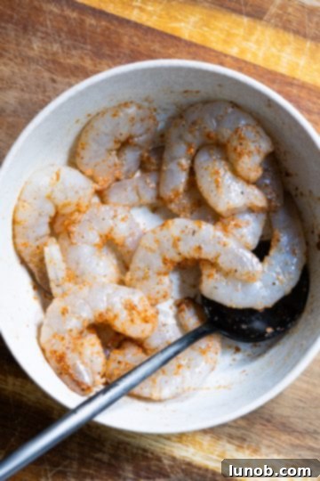 Fiery Fra Diavolo Shrimp Linguine 4 Seasoned raw shrimp with cayenne, garlic powder, salt, and pepper in a mixing bowl, ready for cooking.