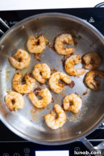 Fiery Fra Diavolo Shrimp Linguine 5 Searing seasoned shrimp in a hot saucepan, ensuring a single layer for even cooking.
