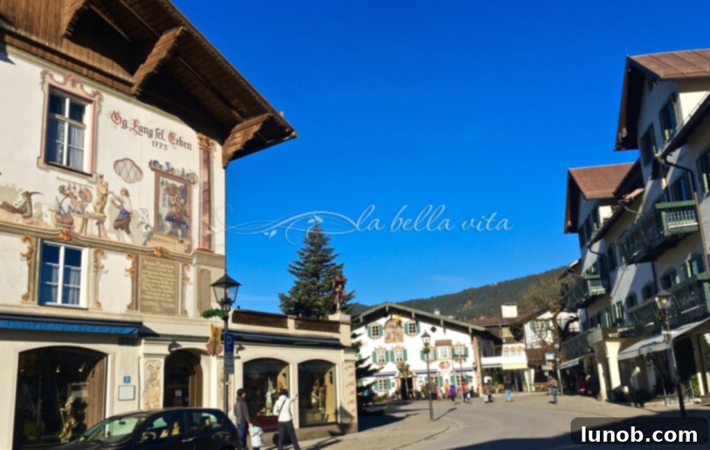 IMG_6180. A wide street in Oberammergau lined with painted buildings and traditional architecture, showcasing the village's unique charm.