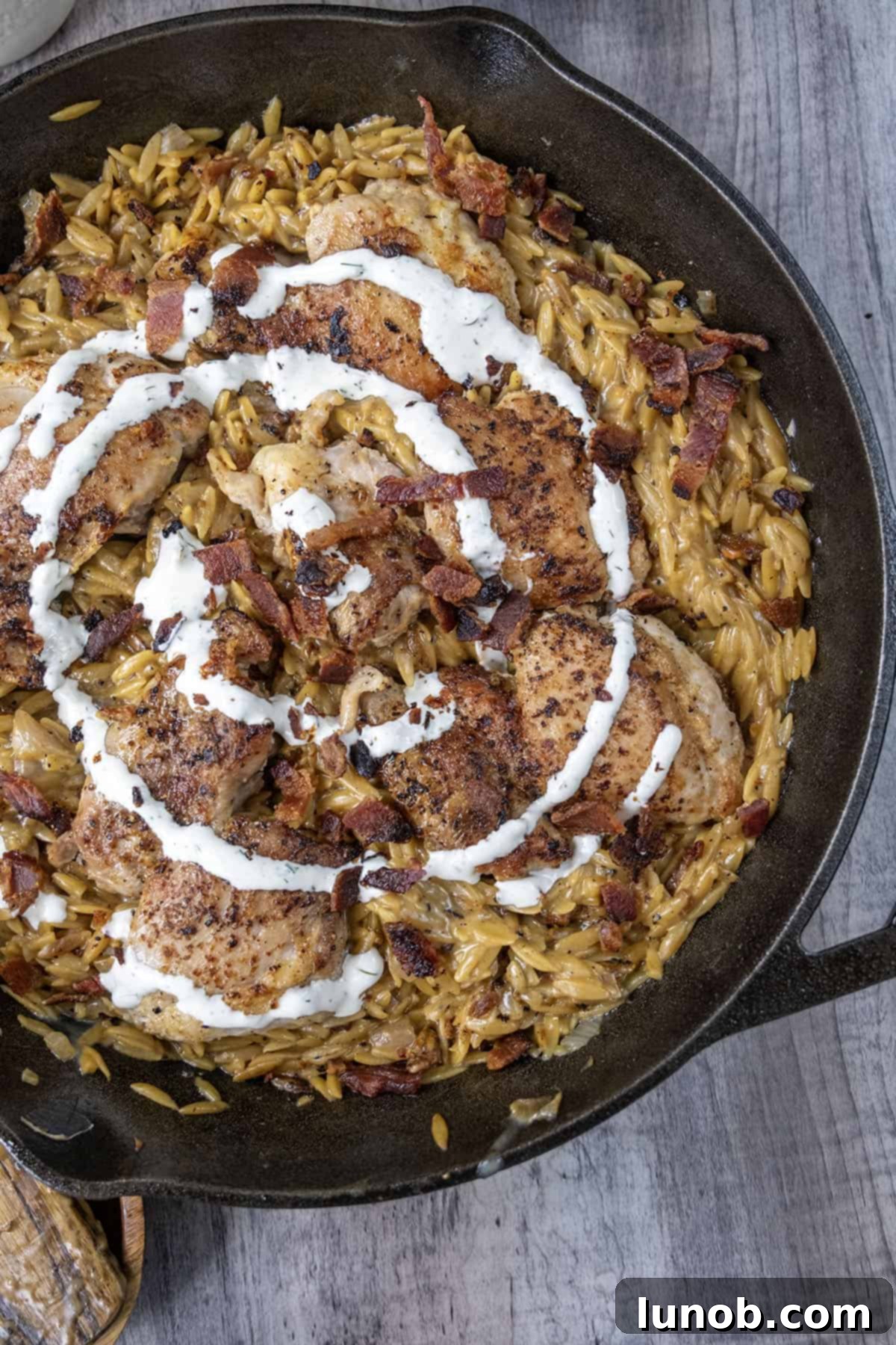 Delicious and creamy Chicken Bacon Ranch Orzo Skillet with golden brown chicken thighs and chopped crispy bacon.
