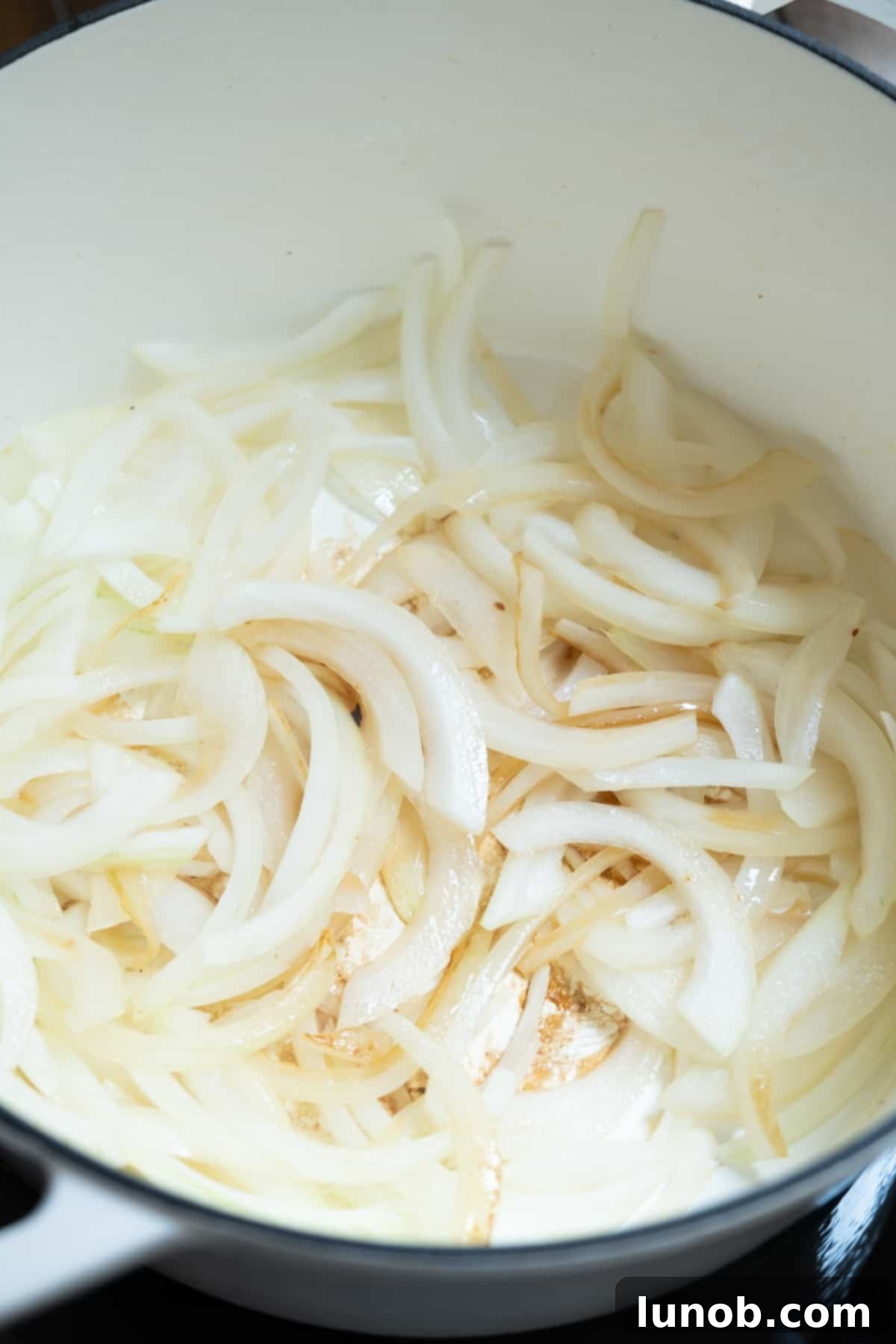 Sliced onions beginning to sauté and soften in a Dutch oven