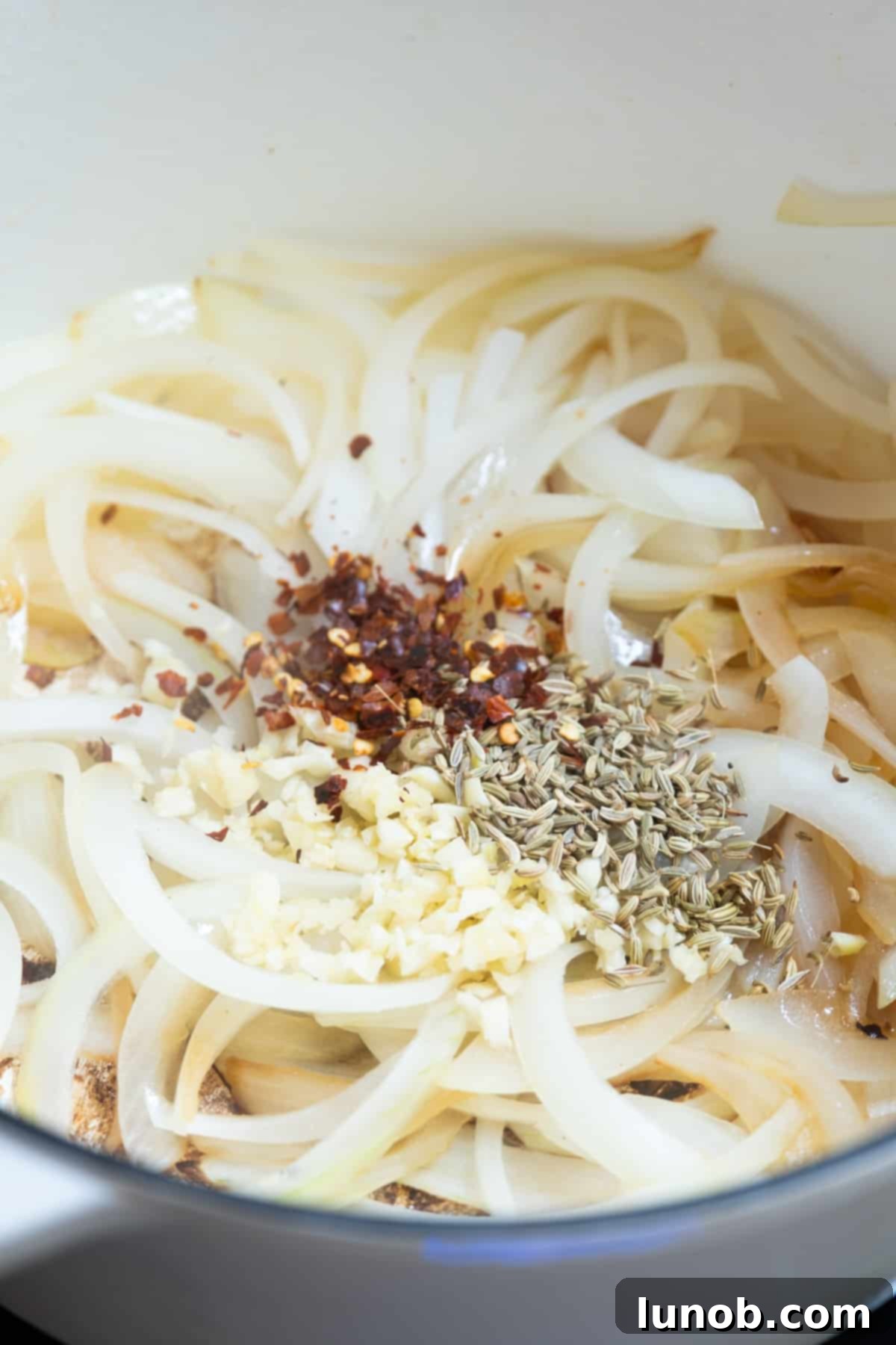 Sauteed onions with minced garlic, fennel seeds, and crushed red pepper added to the Dutch oven