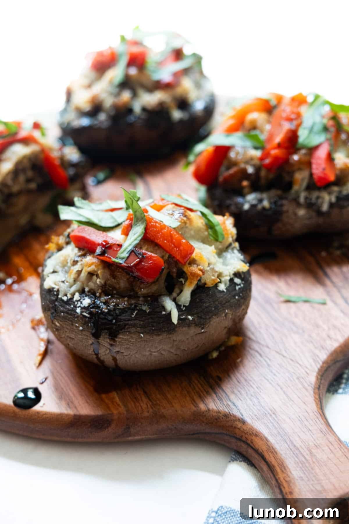 Gourmet Italian Stuffed Portobello Bake 2 Close up of baked Italian stuffed portobello mushroom stuffed with sausage and topped with cheese, roasted red peppers and basil