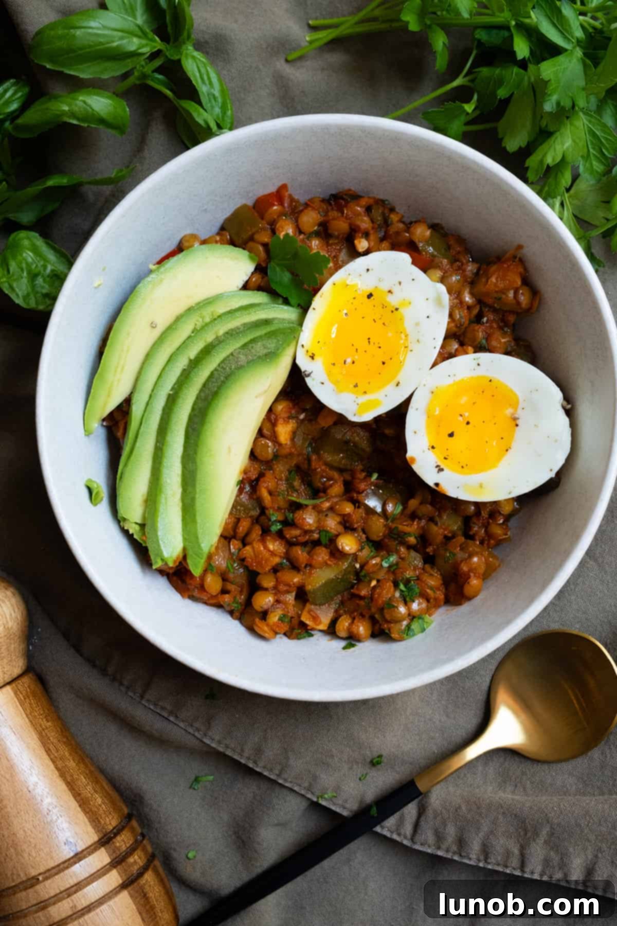 Wholesome Lentil Egg Breakfast 2 soft boiled Eggs and Lentils in tomato sauce for breakfast with sliced avocado and fresh herbs