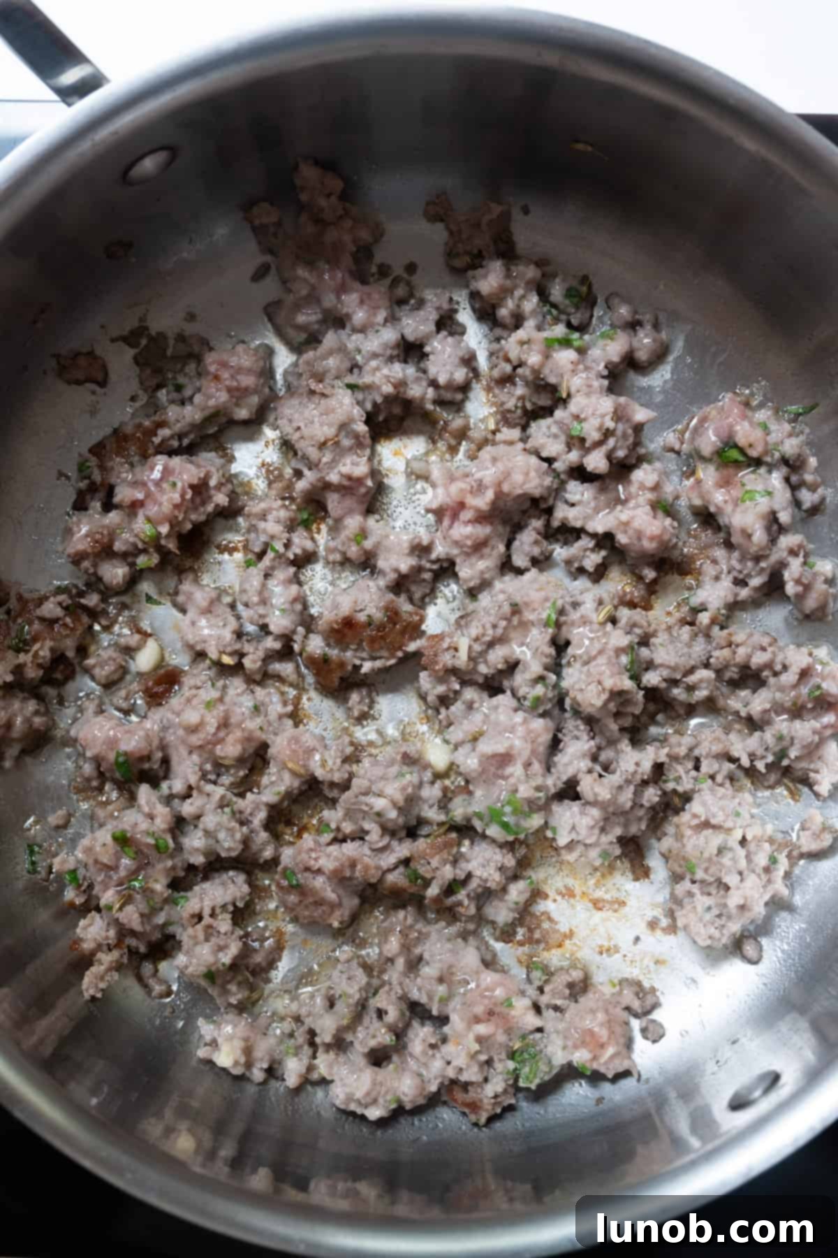 Sweet Italian sausage browning and developing a crust in a hot pan.