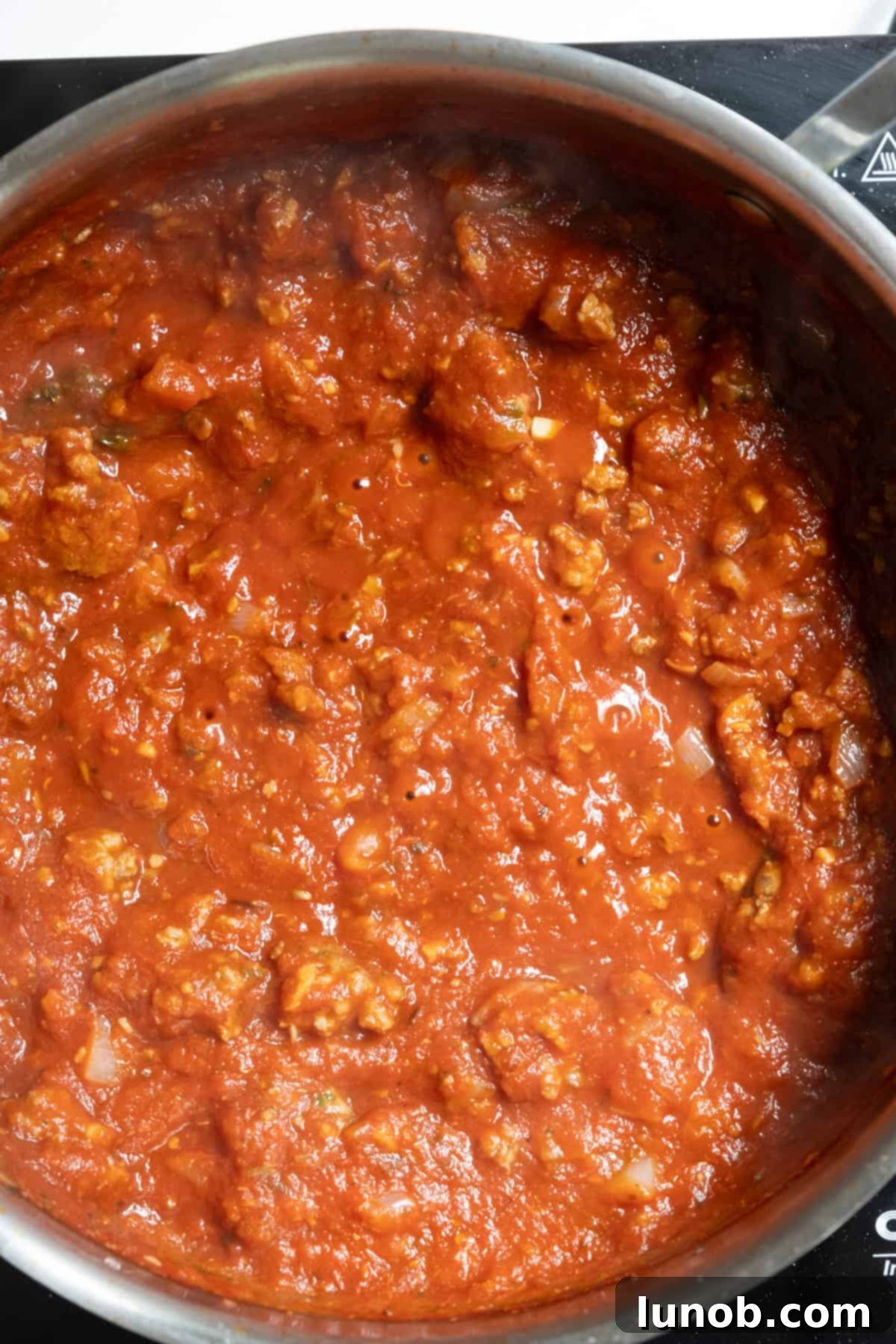 Cooked sausage returned to the simmering pink sauce, infusing flavor.