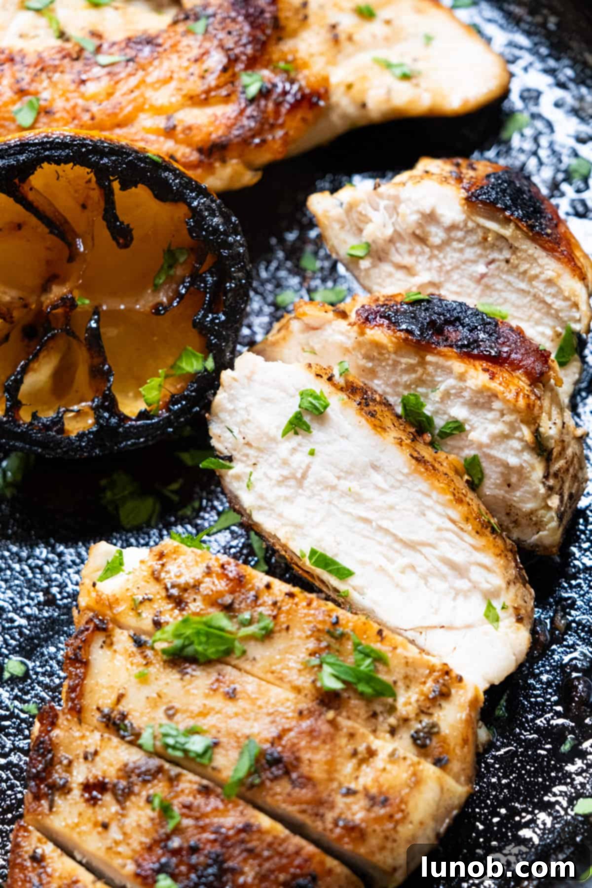 The Ultimate Cast Iron Chicken Breast 2 The perfectly juicy cast iron chicken breast sliced and laid on the cast iron skillet, showcasing its golden-brown crust and tender interior.