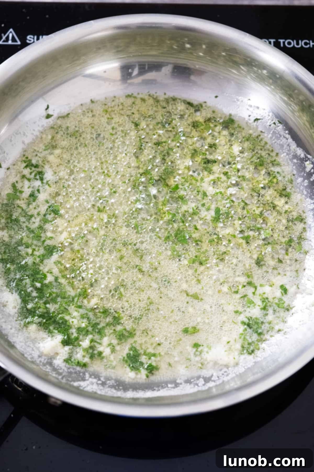Crispy Air Fryer Garlic Parmesan Wings 6 Garlic butter sauce with fresh parsley simmering gently in a small saucepan on low heat