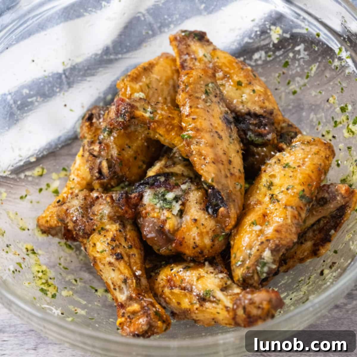 Crispy Air Fryer Garlic Parmesan Wings 7 Air fryer garlic parm wings tossed in sauce and piled on a white plate