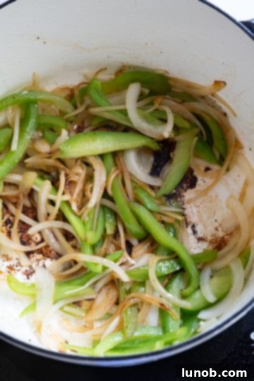 Homemade Restaurant-Style Chicken Scarpariello Perfection 7 Sautéed peppers and onions glistening in a Dutch oven, ready for garlic