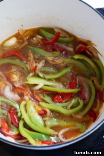 Homemade Restaurant-Style Chicken Scarpariello Perfection 8 Cherry peppers and sauce simmering in white wine in a Dutch oven