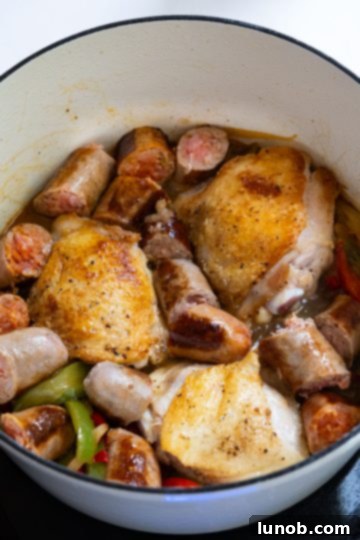 Homemade Restaurant-Style Chicken Scarpariello Perfection 9 Chicken and sausage added back to the simmering sauce in a Dutch oven