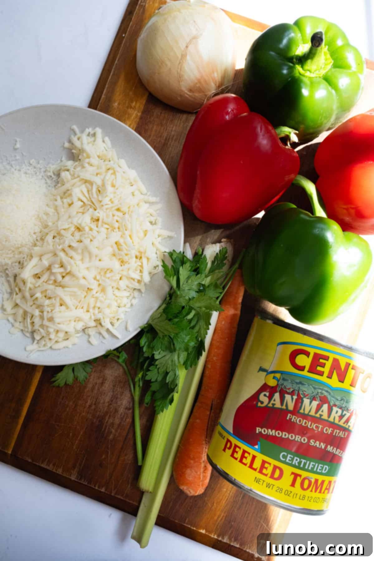 A colorful array of ingredients laid out on a wooden board, including bell peppers, ground beef, rice, tomatoes, and herbs, ready for making stuffed peppers.