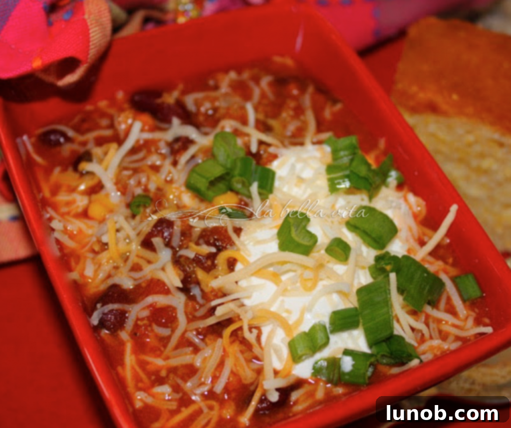 Winning Game Day Eats For Every Fan 22 A steaming bowl of spicy hot chili, garnished with cheese and green onions.