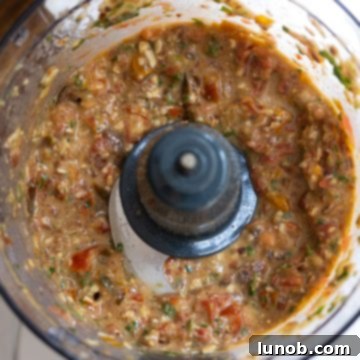 Sicilian Sun-Kissed Busiate 5 Cherry tomatoes and olive oil being added to the pesto mixture in a food processor.