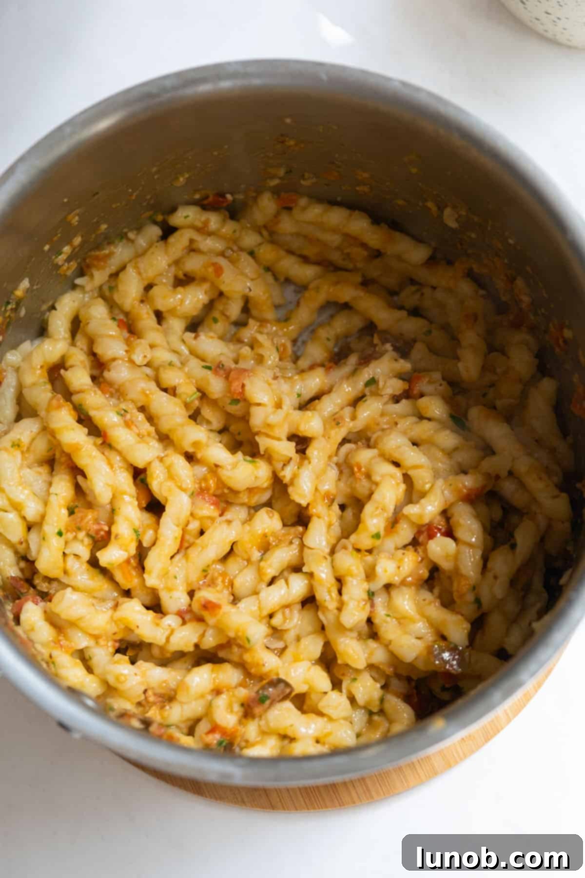 Sicilian Sun-Kissed Busiate 8 Pasta and pesto being stirred together in the pot where the pasta was boiled, ensuring thorough coating.
