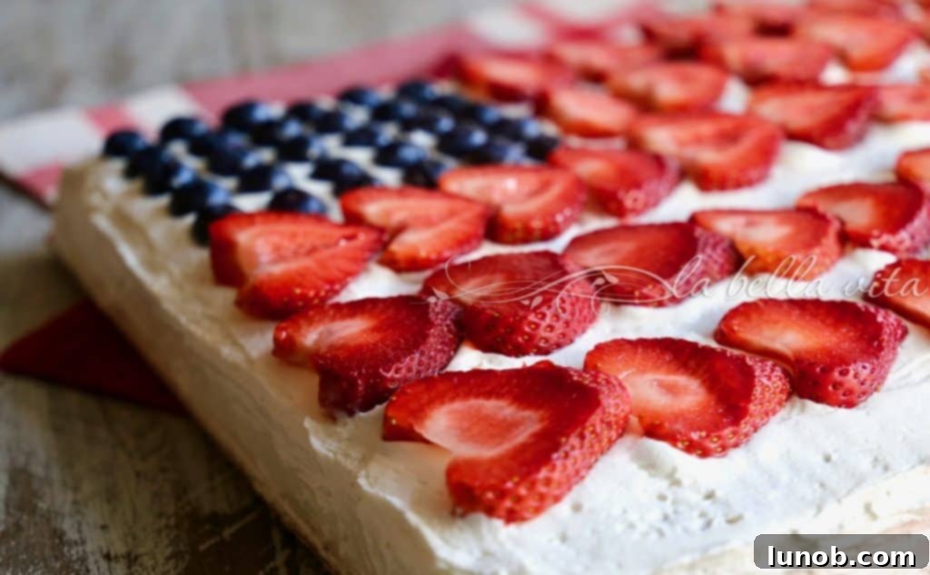 Ina Garten's Legendary Red White and Blue Flag Cake 2 A vibrant Red, White, and Blue Flag Cake adorned with fresh blueberries and raspberries, sitting on a white cake stand against a rustic background. Perfect for patriotic holidays.