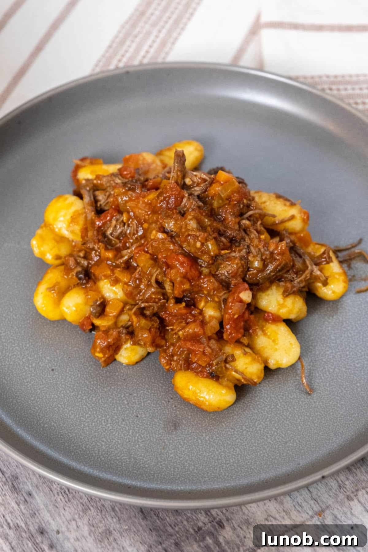 Rich Italian short rib ragu served over soft potato gnocchi, ready for a comforting meal.