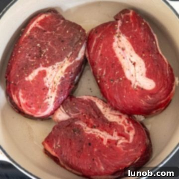 Short ribs searing in a hot Dutch oven, developing a rich brown crust.