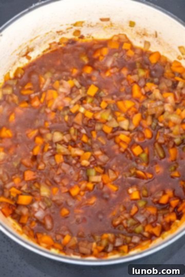 Red wine simmering in the Dutch oven with vegetables and pancetta.