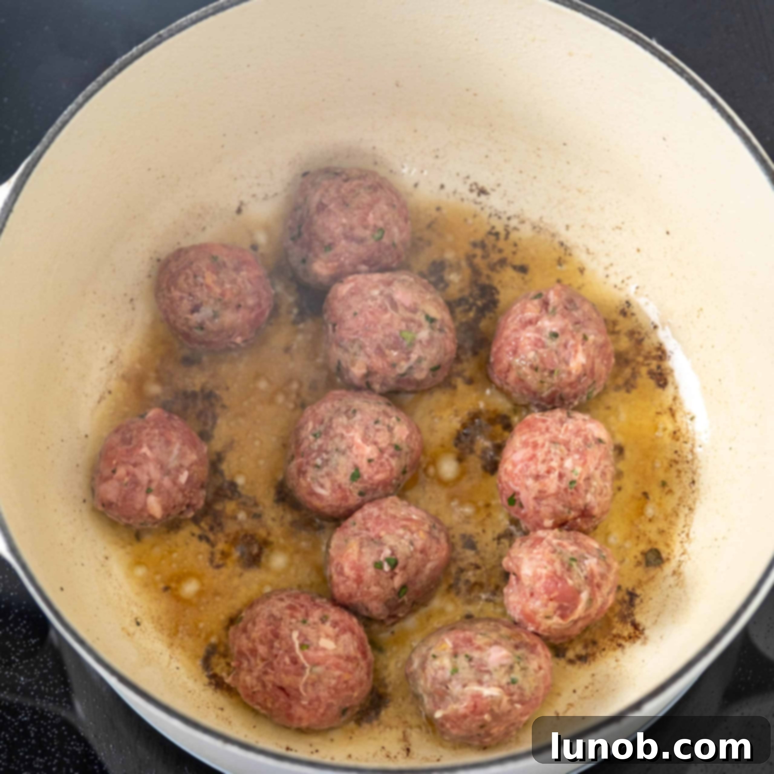 Rustic Italian Meatball & Escarole Soup 5 Mini Italian meatballs frying in olive oil in a large pot, developing a golden crust.