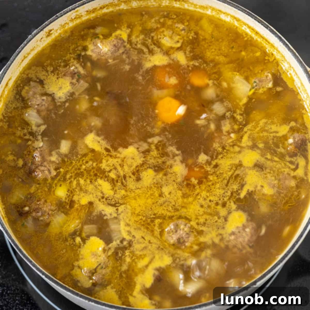 Rustic Italian Meatball & Escarole Soup 7 Italian wedding soup simmering in a pot with meatballs and vegetables.