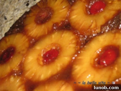 A glorious shot of the Pineapple Upside-Down Cake after being flipped, revealing the sticky, sweet caramel and fruit topping.