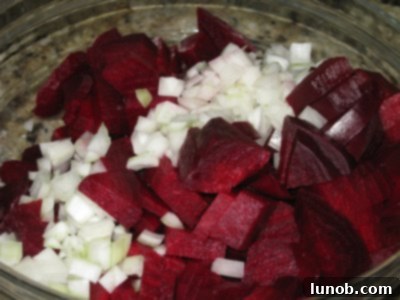An assembled Italian Beet Salad in a glass bowl, showcasing the sliced beets, sweet onions, and a glistening balsamic vinaigrette with herbs