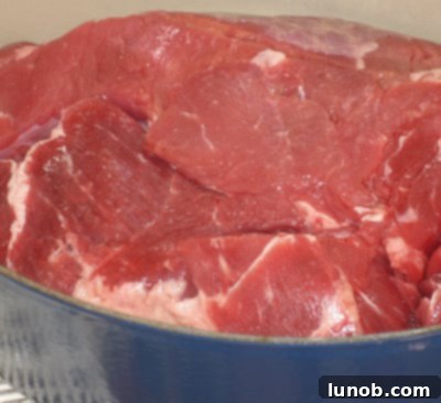 Chuck roast searing in a heavy pot, developing a rich caramel brown crust.