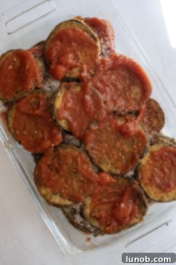 Our Eggplant Parmigiana Superior To Olive Garden 8 Layering eggplant with sauce in a baking dish.