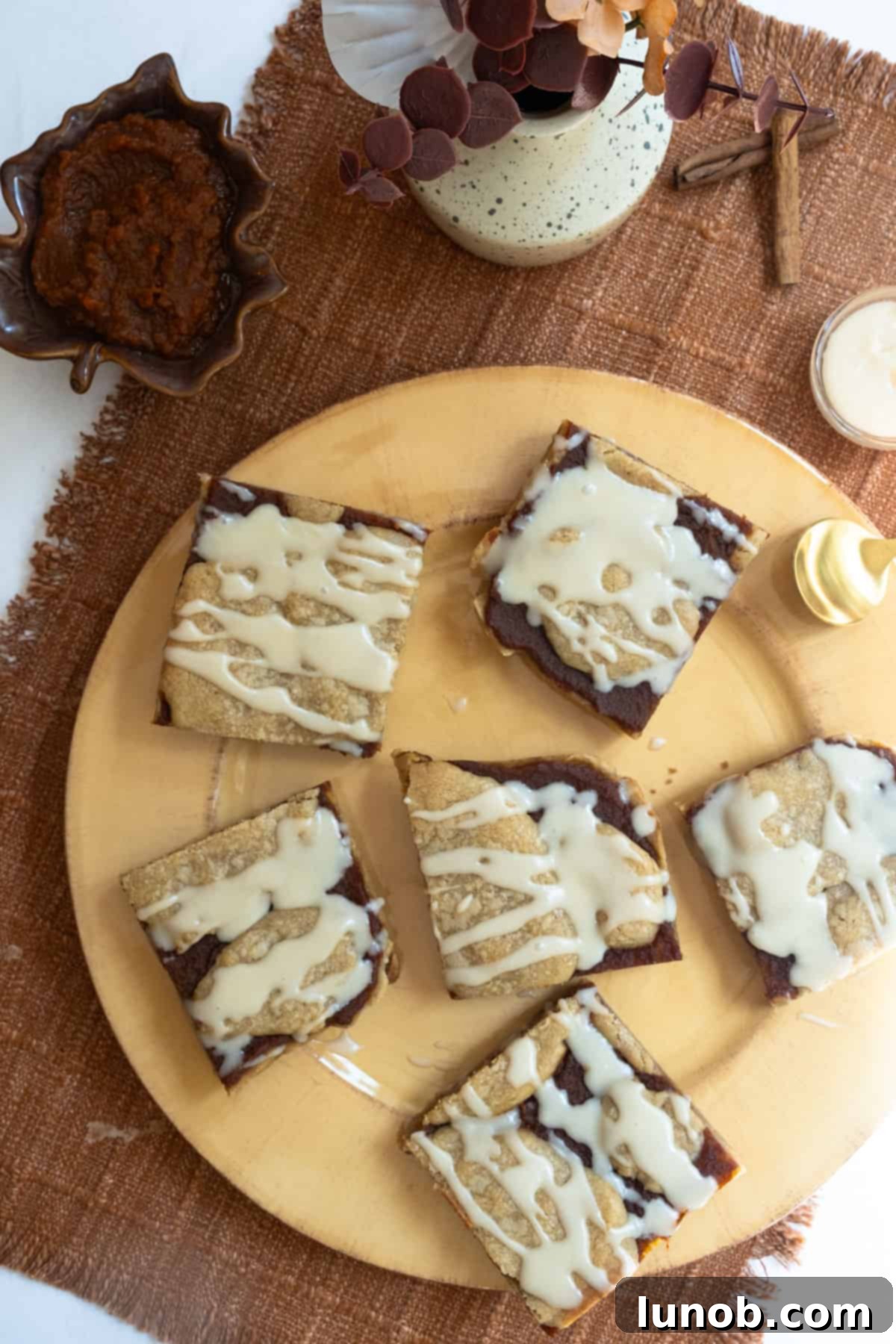 pumpkin butter blondies with maple glaze, drizzled with sweet topping on a cooling rack