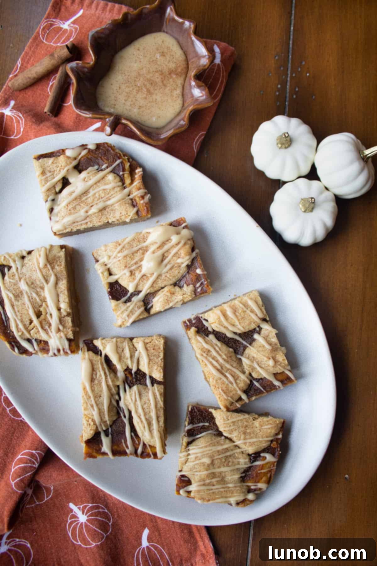 Pumpkin Butter blondies drizzled with maple glaze, with a side dish of extra maple glaze for dipping.