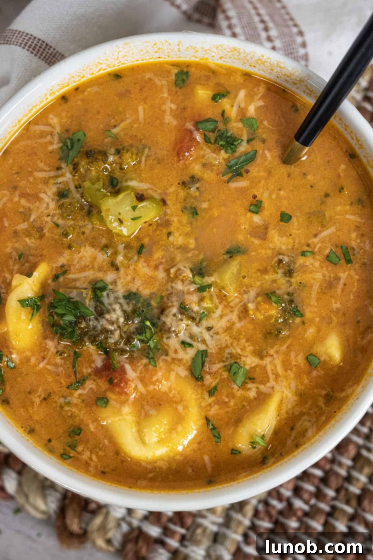 Rustic Italian Tortellini Soup topped with fresh parmesan and herbs, ready to be served