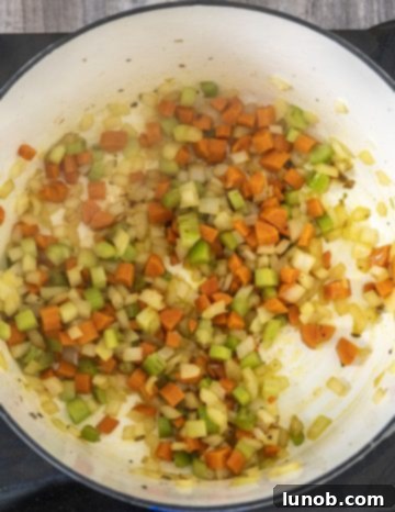 Carrots, onions, and celery sautéing with minced garlic in a dutch oven