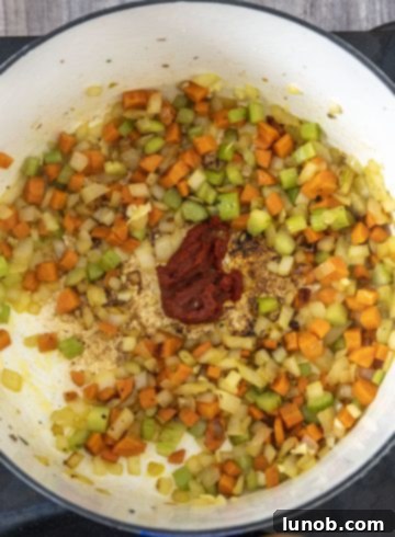 Tomato paste added to a small well in the center of sautéed vegetables in a dutch oven