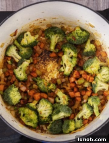 Chopped broccoli florets added to the simmering vegetables and tomato paste