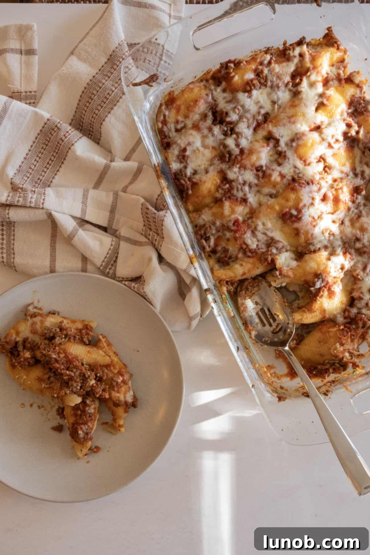 Italian stuffed shells with meat sauce and ricotta, baked to golden perfection in a glass dish.