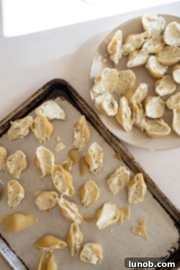 Jumbo pasta shells being generously stuffed with creamy ricotta filling.